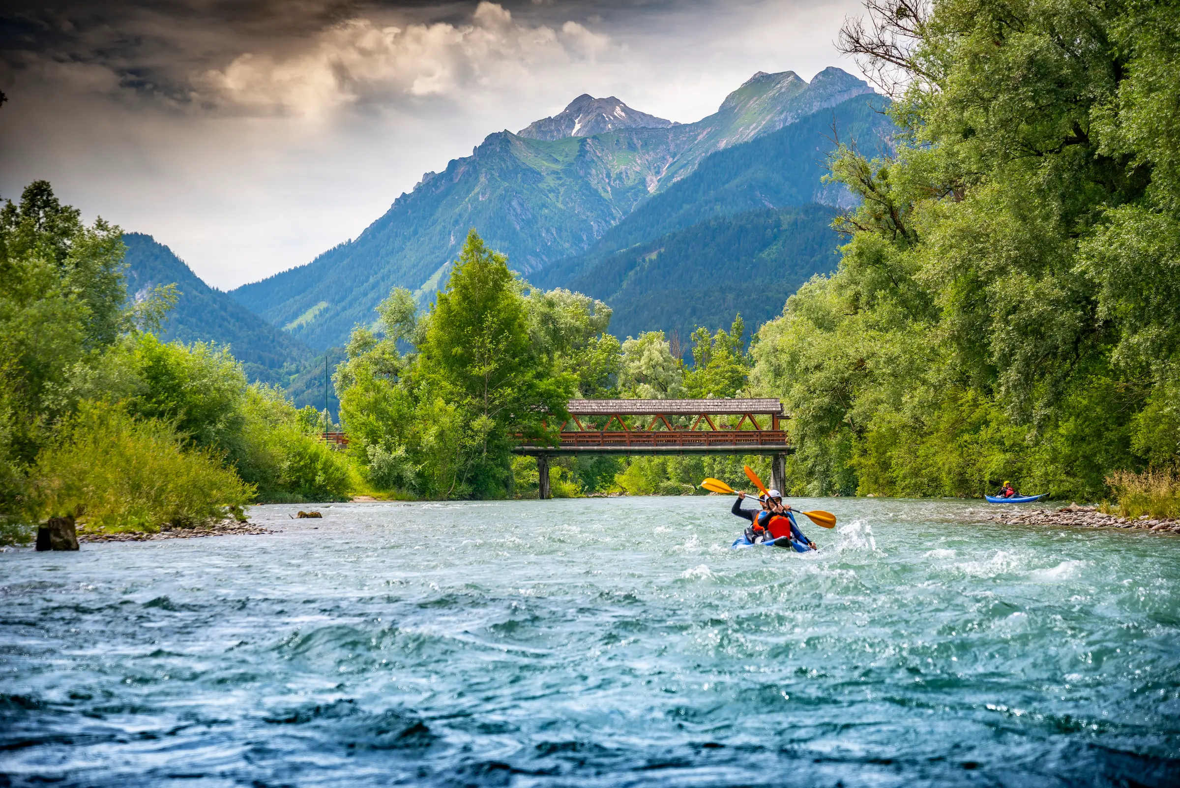 Kajakfahrer auf dem Fluss unter einer Holzbrücke