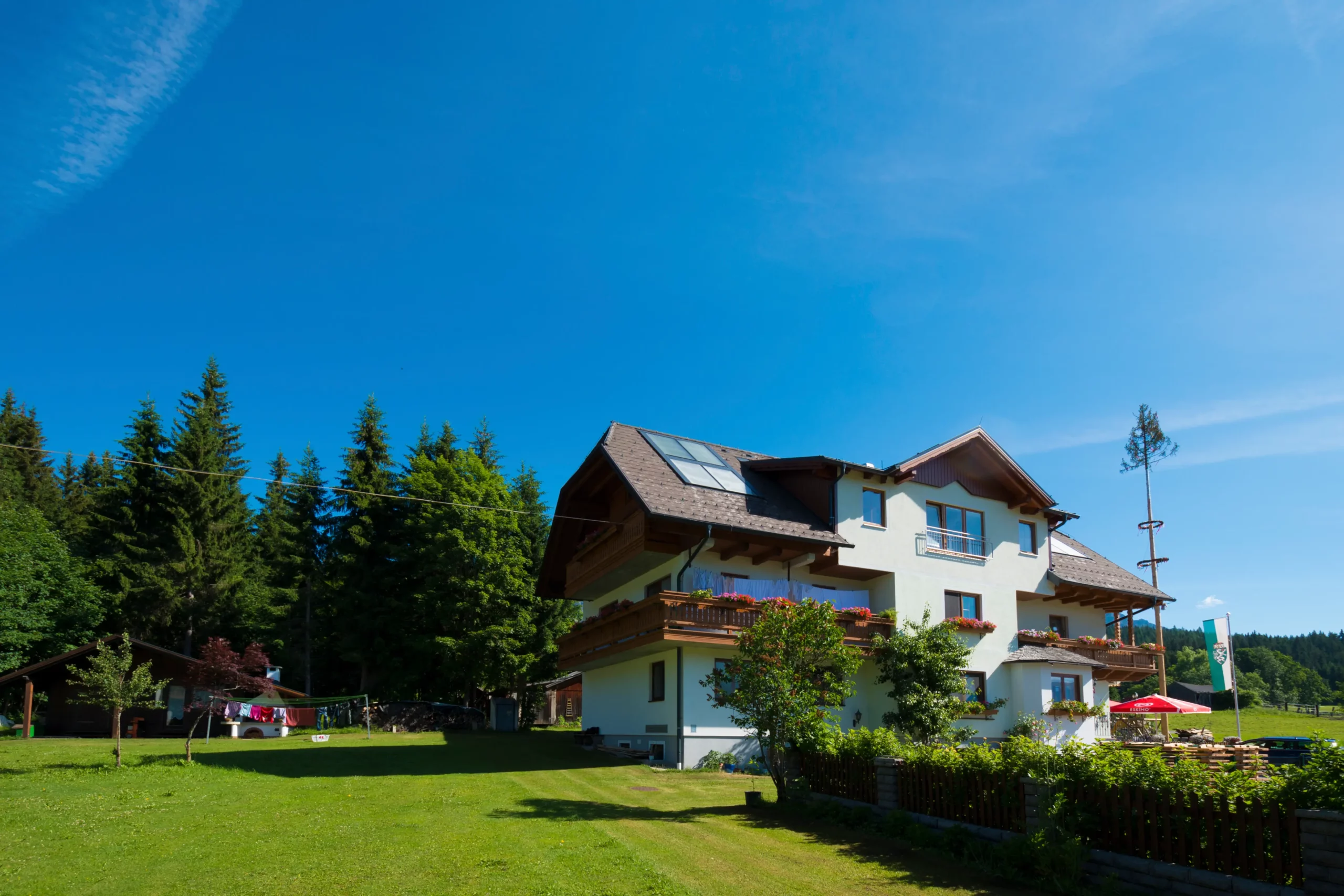 Alpengasthof Fichtenheim im Sommer mit Wiese und Tannen